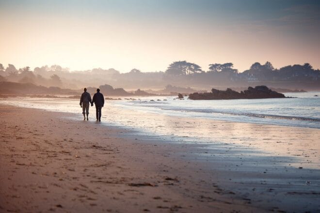Vue pittoresque d un couple se promenant main dans la main sur une plage paisible de bretagne au coucher du soleil